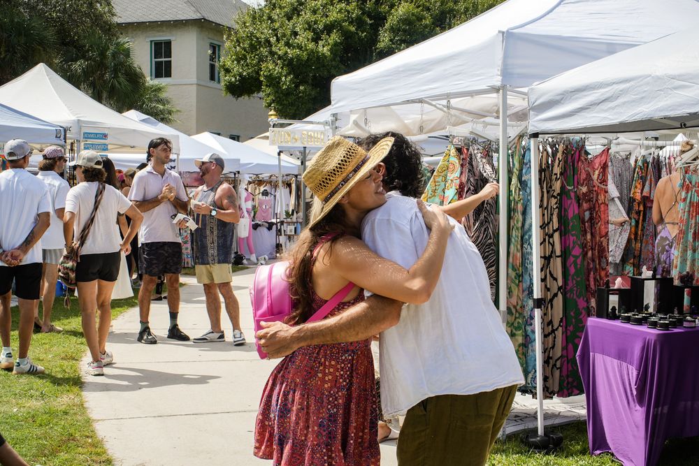 Two friends embracing in the aisle between vendor tents.