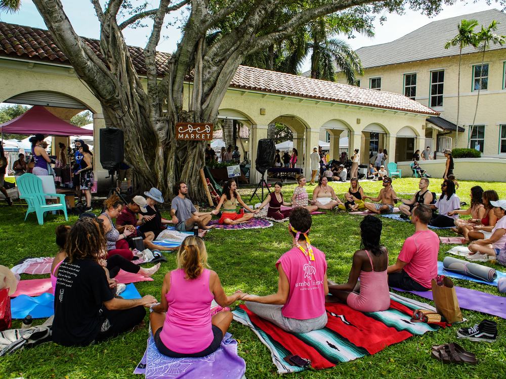 Attendees seated in a circle on the grass holding hands during the Heart Circle.