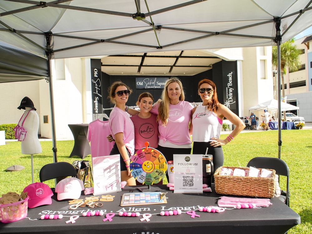 The SALT Pilates booth, decorated in pink with ribbons along the table.