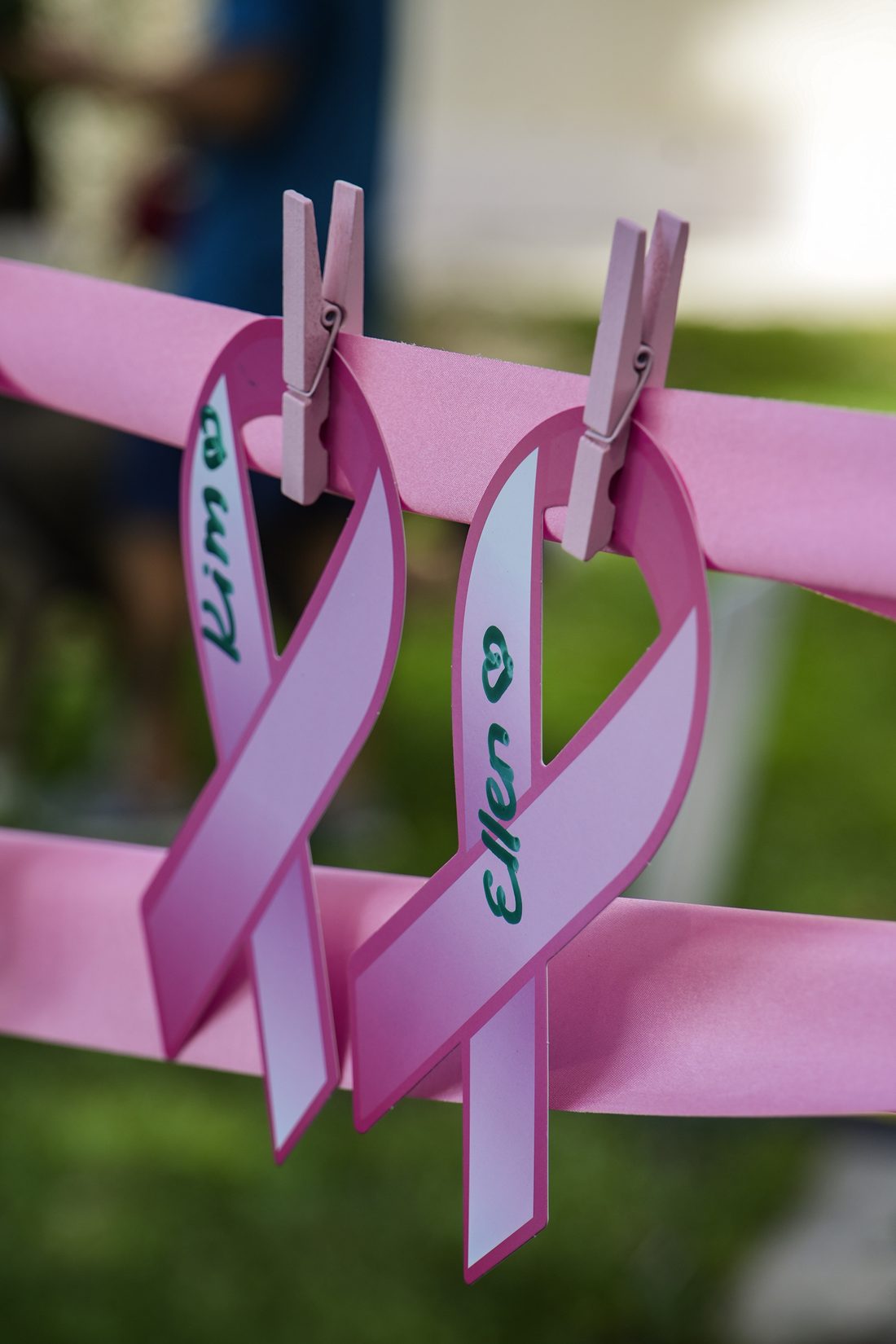 Two hand-written pink ribbons pinned to the tree at last year's Together In Community, each bearing a loved one's name.